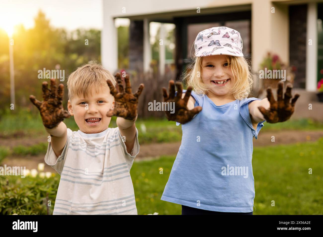 cheerful kids showing dirty muddy hands outdoors in garden Stock Photo