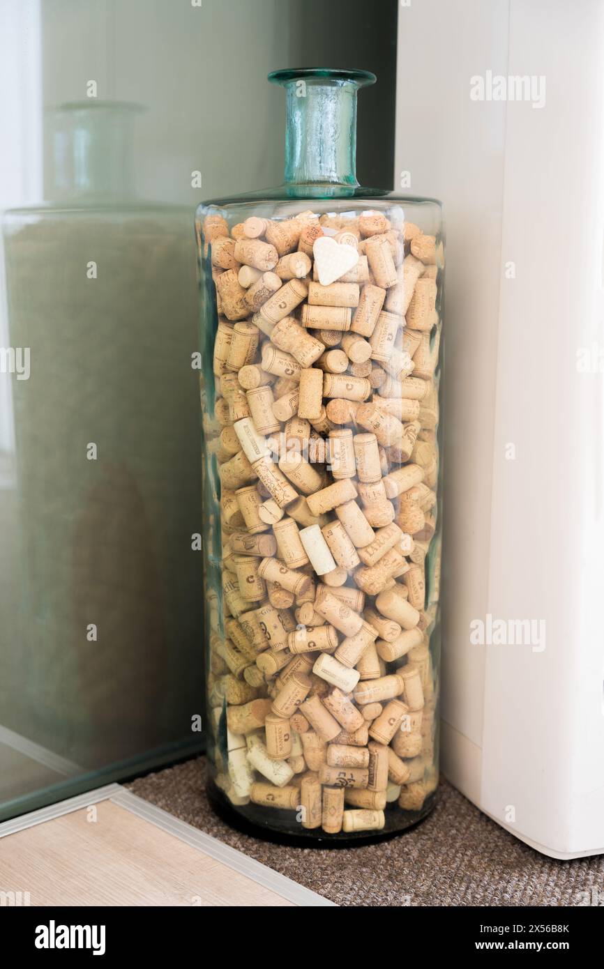 A large transparent decorative bottle filled with a collection of wine corks. Wine collector decor Stock Photo