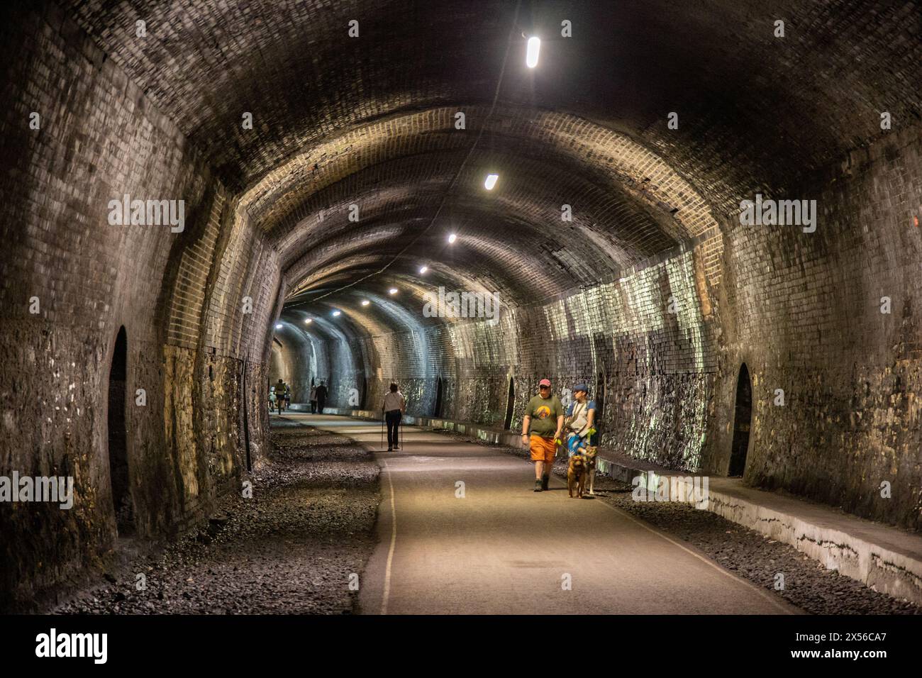 People waling through the Headstone Tunnel on the Monsal Trail as it passes through the hillside at Monsal Head in the Derbyshire Peak District England Stock Photo