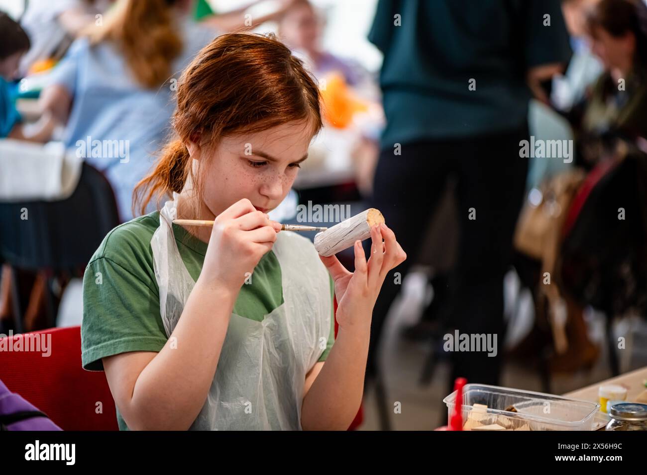 cute teen girl at a master class making a craft from wood, exhibition ...