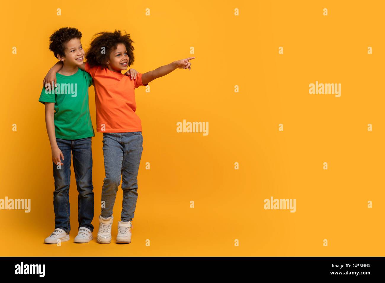 Two Joyful Children Pointing and Looking at Copy Space Stock Photo