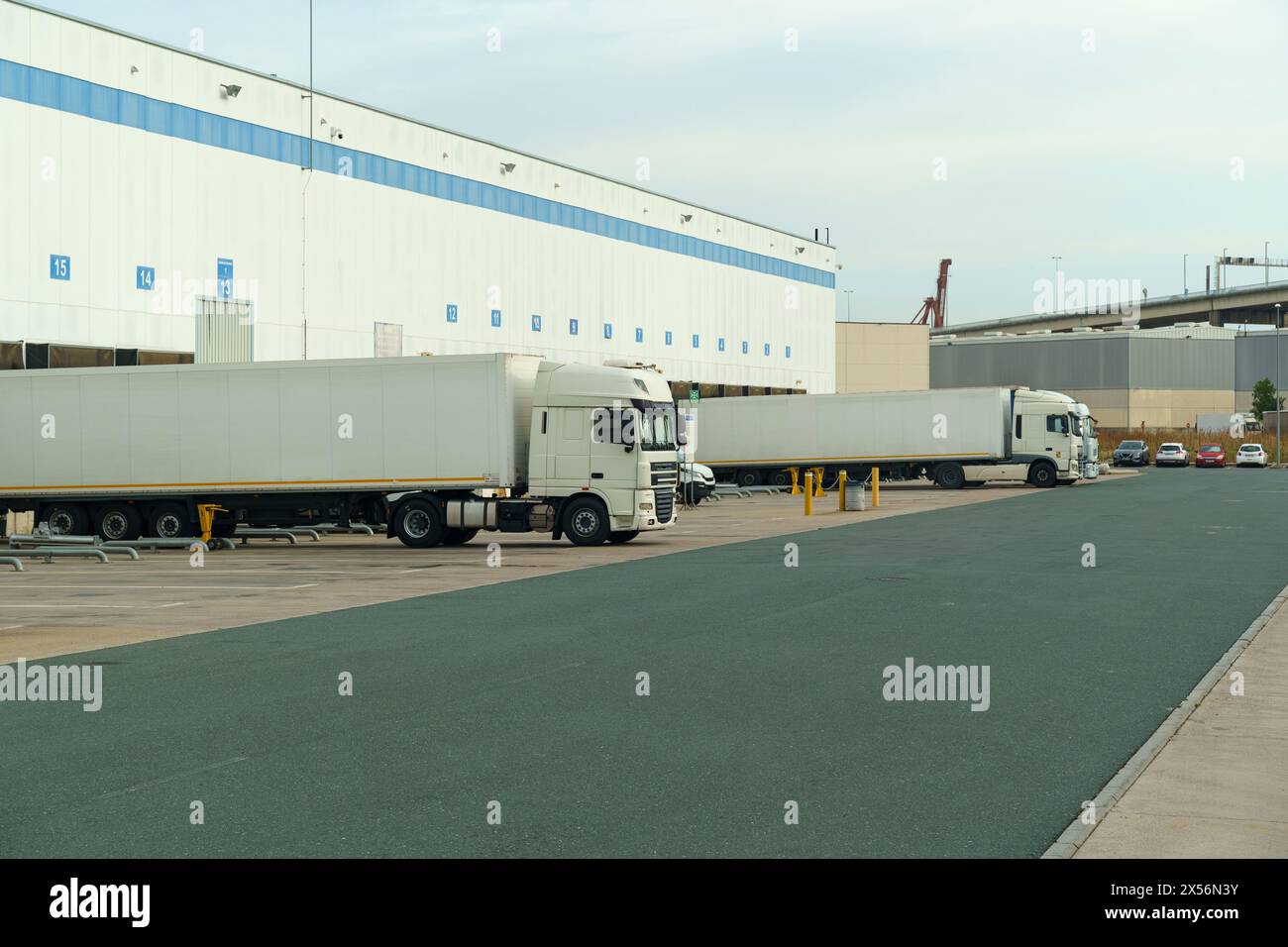 A row of trucks parked neatly in front of a commercial building, showcasing efficient transport and logistics operations. Stock Photo