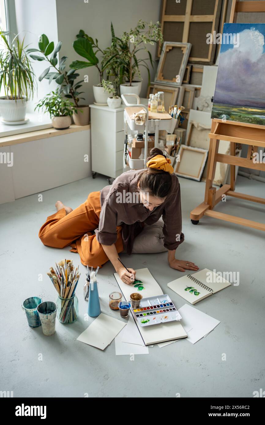 Focused female artist paints with aquarelle. Creative working process of woman painter at art studio Stock Photo