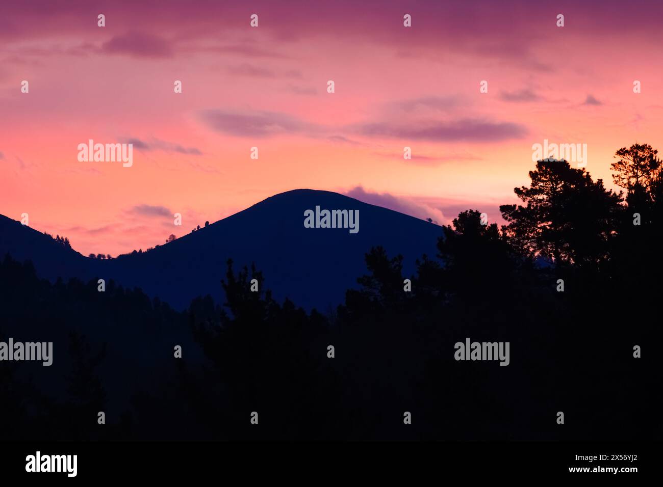 Reddish dawn with the silhouettes of the mountains in the background Stock Photo