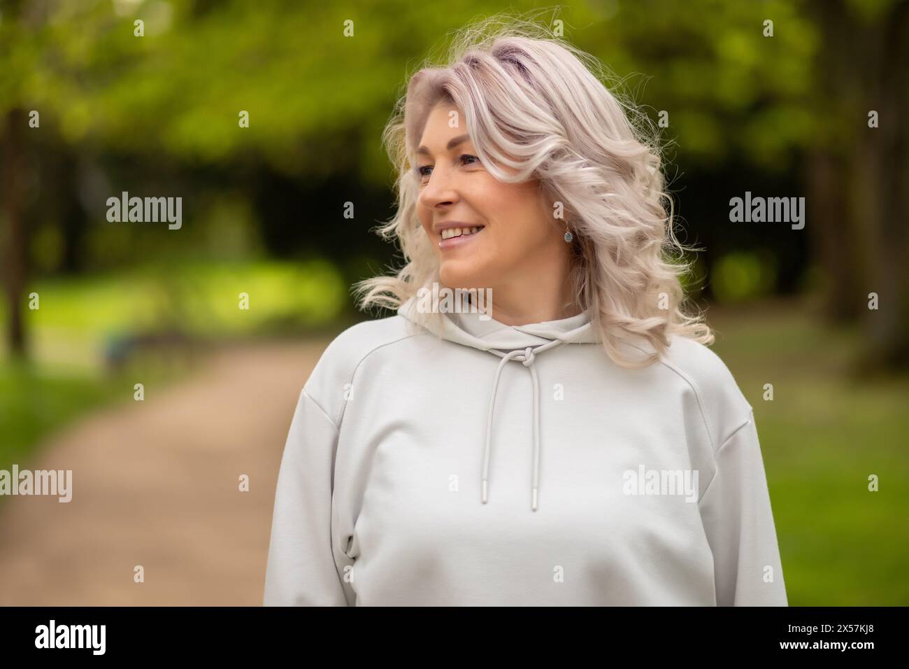 Woman with silver hair smiling in the park. Stock Photo