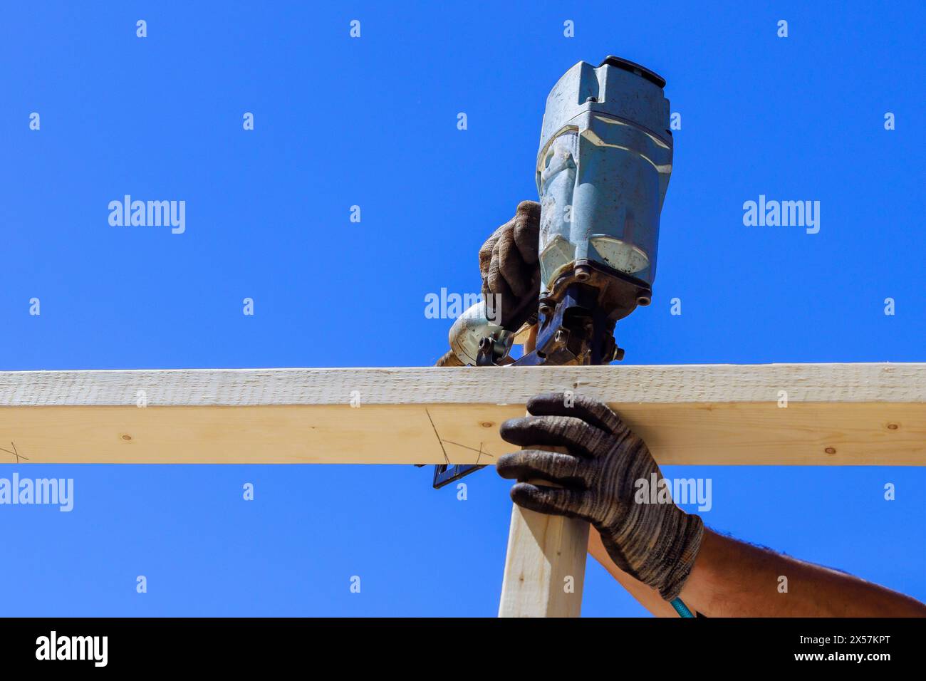 Framer uses an air nail hammer to install beams in wooden frame Stock ...