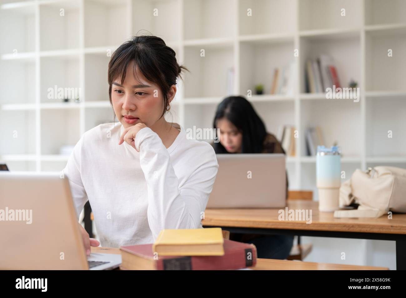 A beautiful young Asian female student focusing on her work on her ...