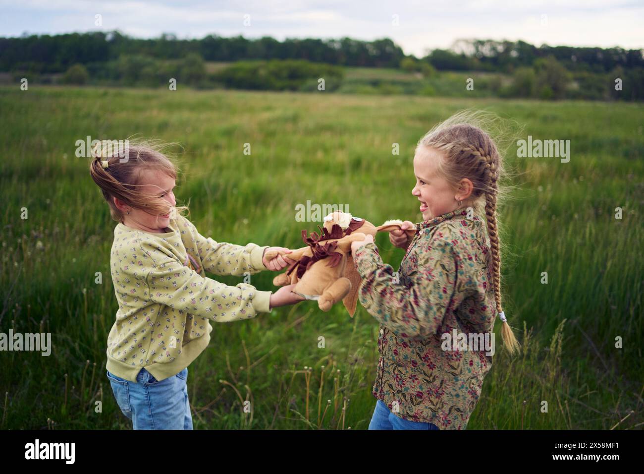 two sisters fight over a toy bunny Stock Photo