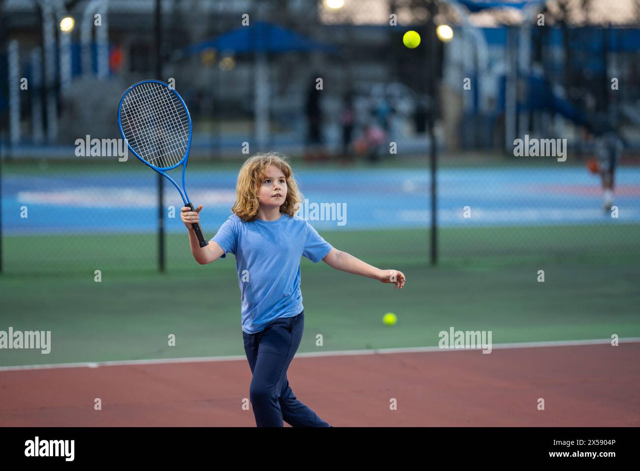 Preteen child swinging racket while training on tennis court at sport ...