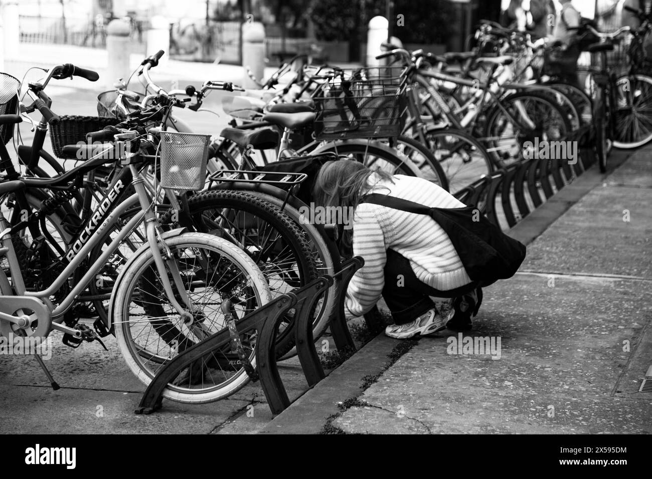 Urban life scene: woman locking her bicycle with a padlock Stock Photo