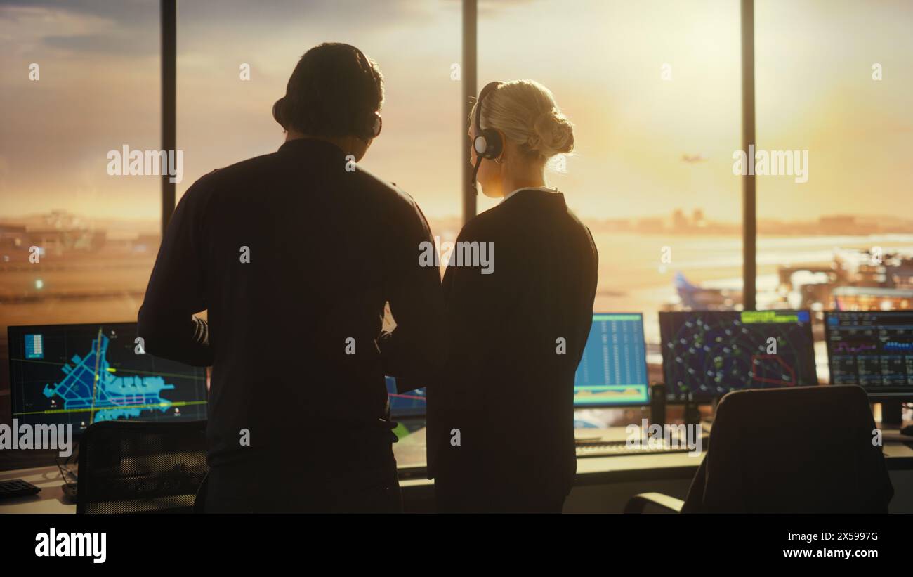 Female and Male Air Traffic Controllers with Headsets Talk in Airport Tower. Office Room Full of Desktop Computer Displays with Navigation Screens, Airplane Flight Radar Data for Controllers. Stock Photo