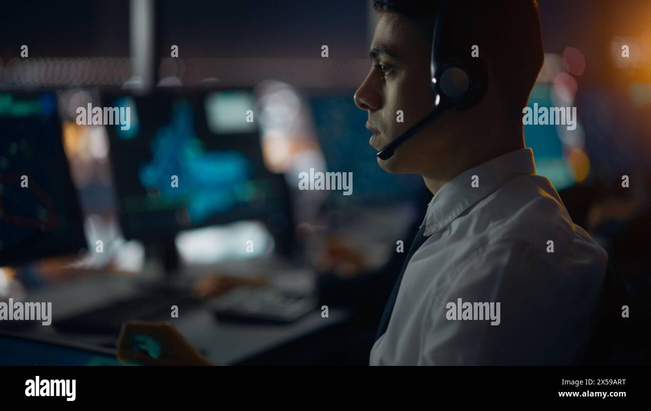 Male Air Traffic Controller with Headset Talk on a Call in Airport Tower. Office Room is Full of Desktop Computer Displays with Navigation Screens, Airplane Departure and Arrival Data for the Team. Stock Photo