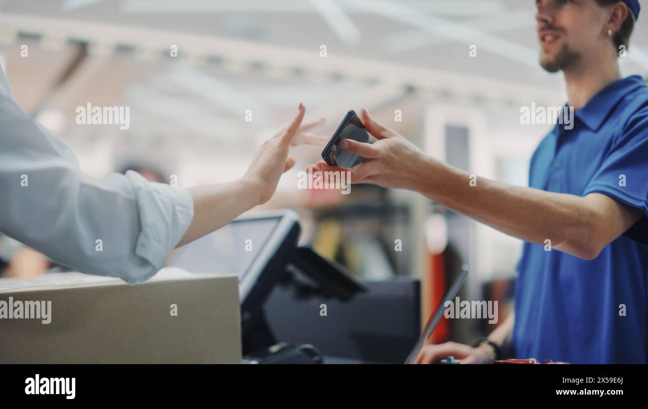 Clothing Store Checkout Cashier Counter: Handsome Courier Takes Package to Deliver for Online Order. Fashion Shop with of Designer Brands Available for Online Shopping and Purchase. Stock Photo