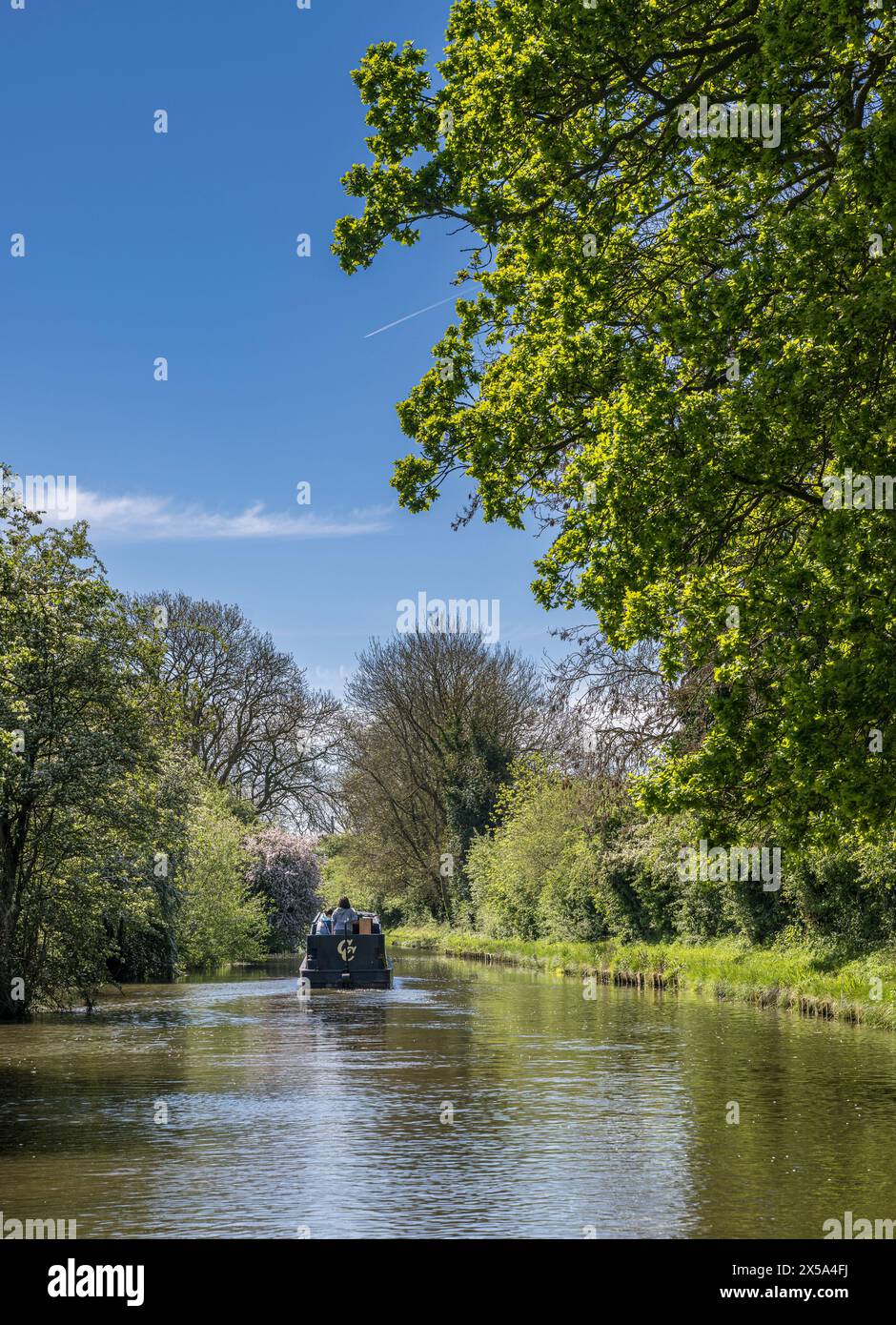 Oxford Canal, Near Rugby, England – A narrowboat on the canal on a bright summer day against a blue sky Stock Photo