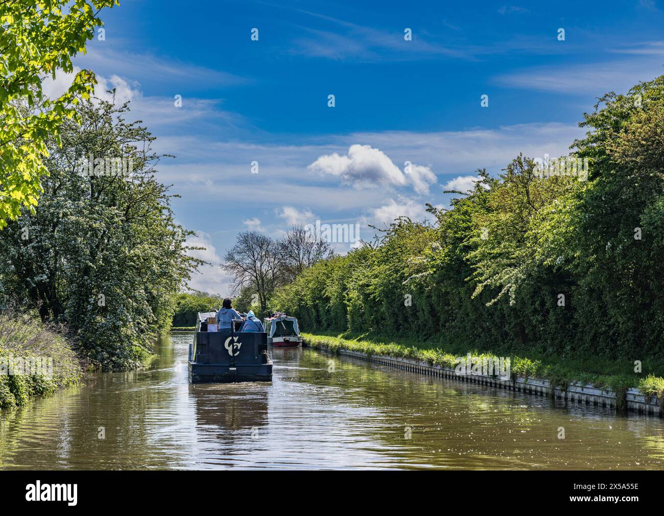 Oxford Canal, Near Rugby, England – A narrowboat on the canal on a bright summer day against a blue sky Stock Photo