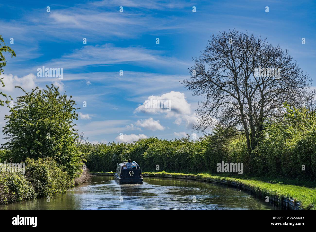 Oxford Canal, Near Rugby, England – A narrowboat on the canal on a bright summer day against a blue sky Stock Photo