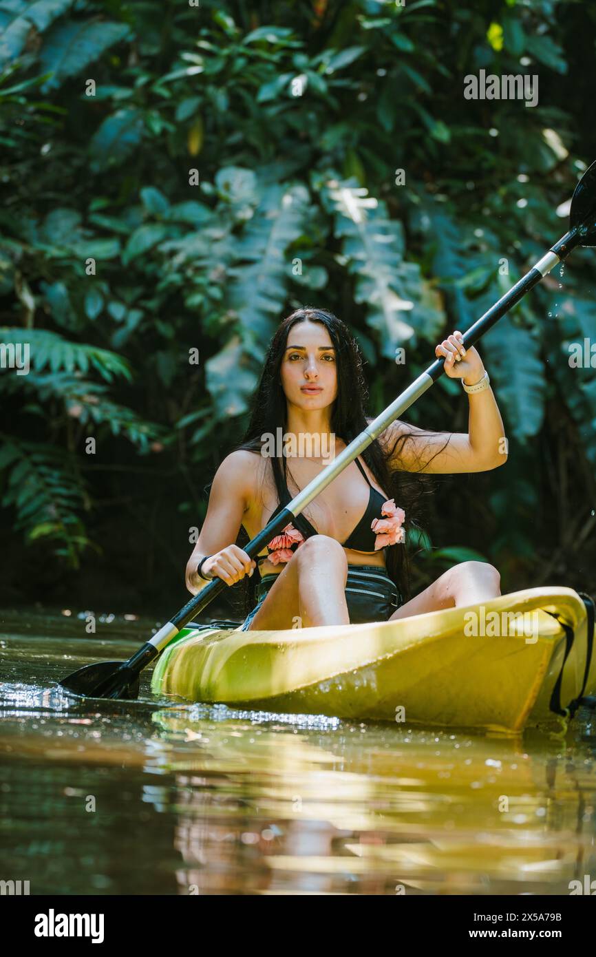 A serene woman kayaking through tranquil waters surrounded by the lush ...