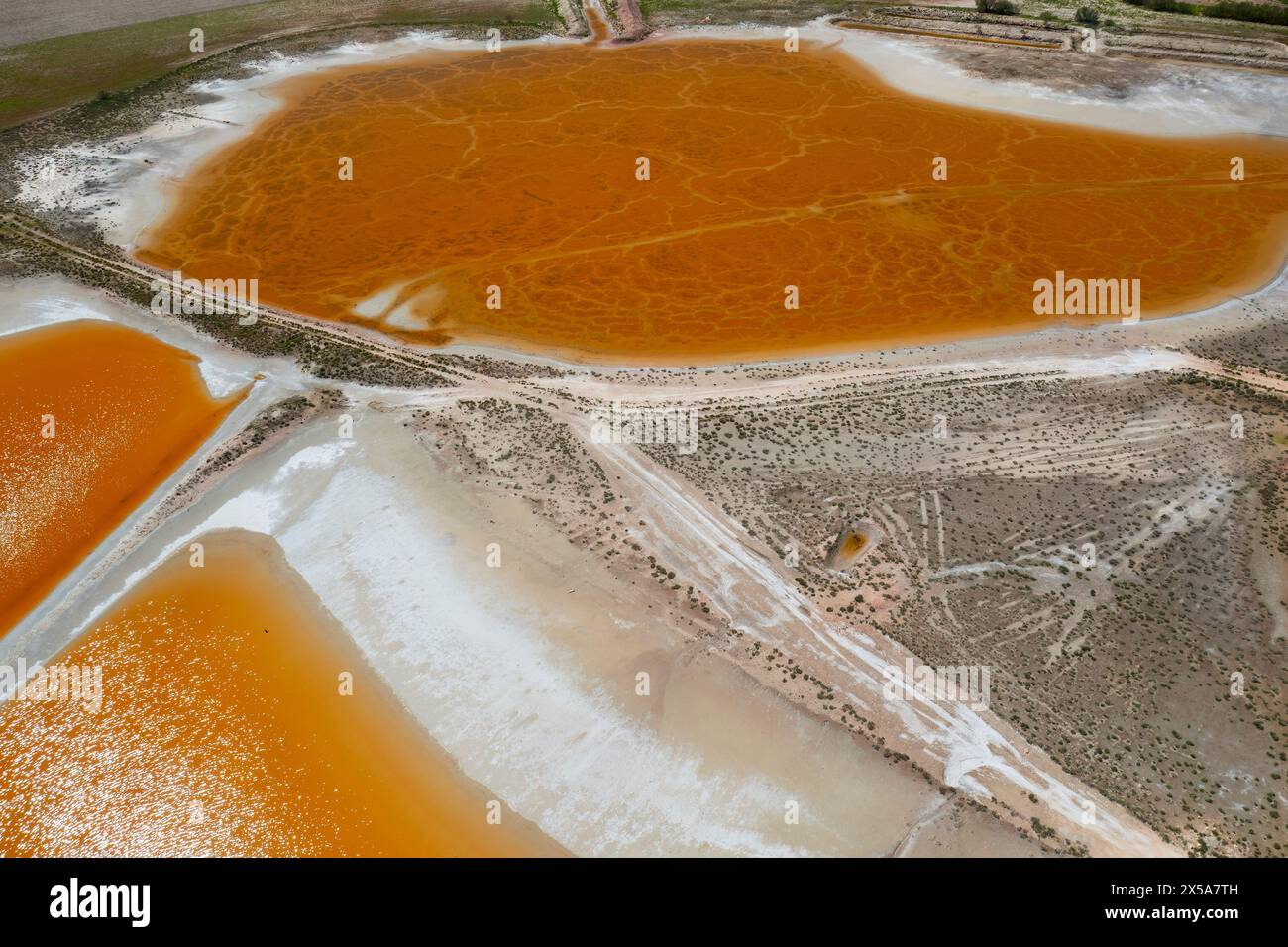 An aerial perspective of colorful salt lagoons with distinctive orange and white hues under the Toledo sunlight, showcasing a striking natural pattern Stock Photo