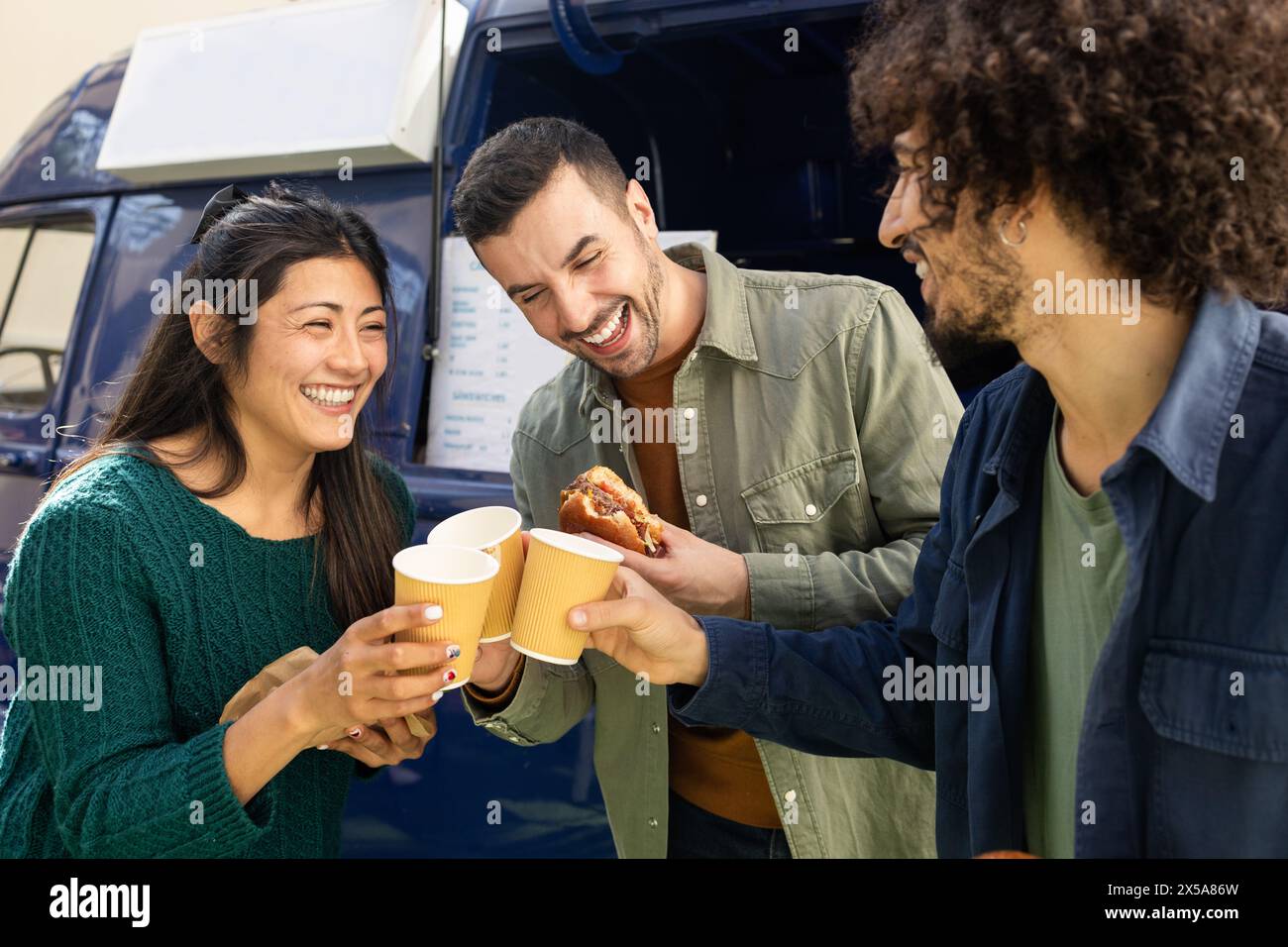 Three friends share a joyful moment over snacks from a food truck Stock Photo