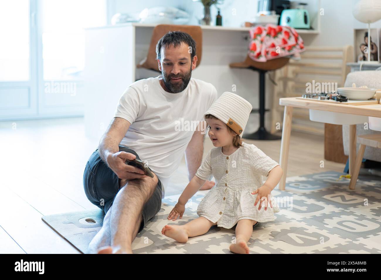 A heartwarming scene of a father and his young daughter sharing a moment together while relaxing on the living room floor Stock Photo