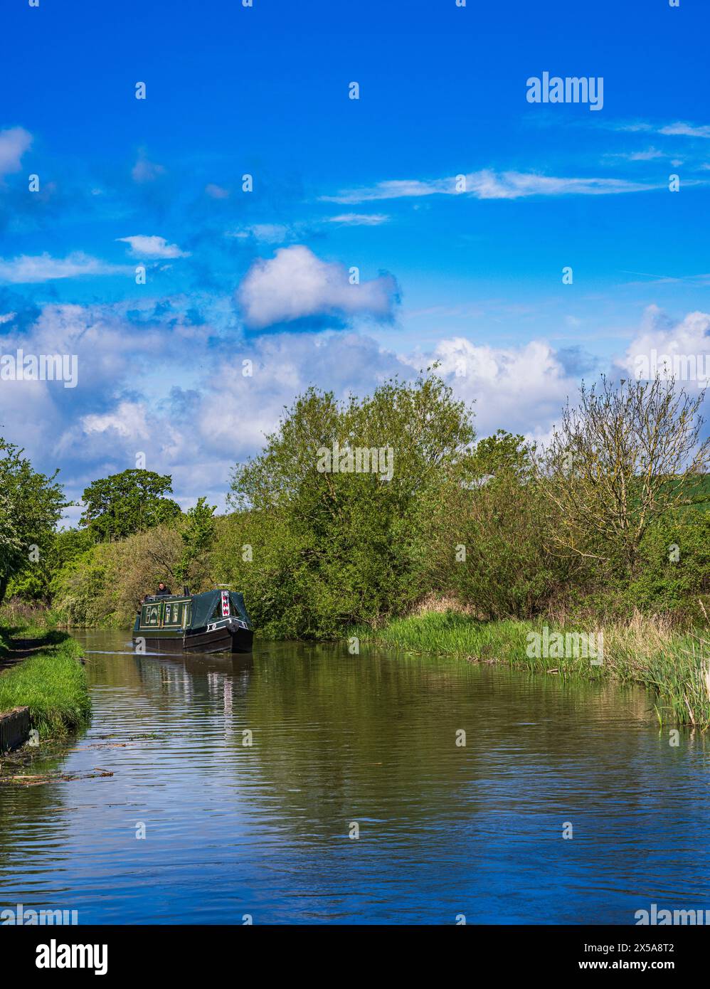 Oxford Canal, Near Rugby, England – A narrowboat on the canal on a bright summer day against a blue sky Stock Photo