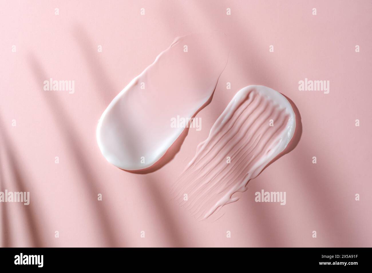 Swatches of cosmetic cream on a pink background, highlighting smooth textures and skincare product consistency Stock Photo