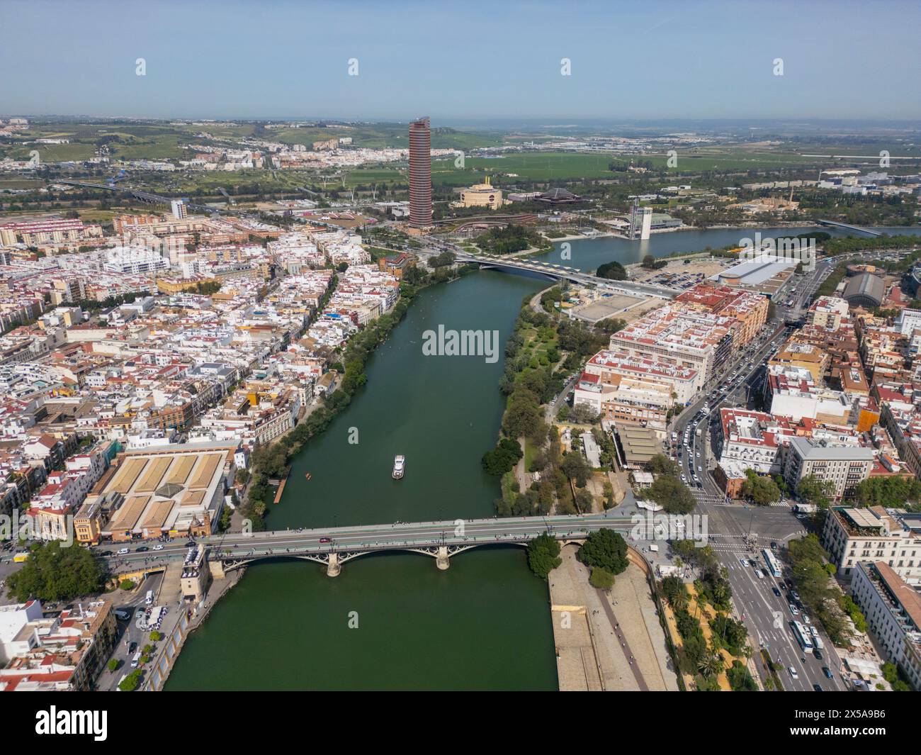 A scenic aerial photograph showcasing Seville's historic architecture, including the iconic cathedral and La Giralda tower by the Guadalquivir River, Stock Photo
