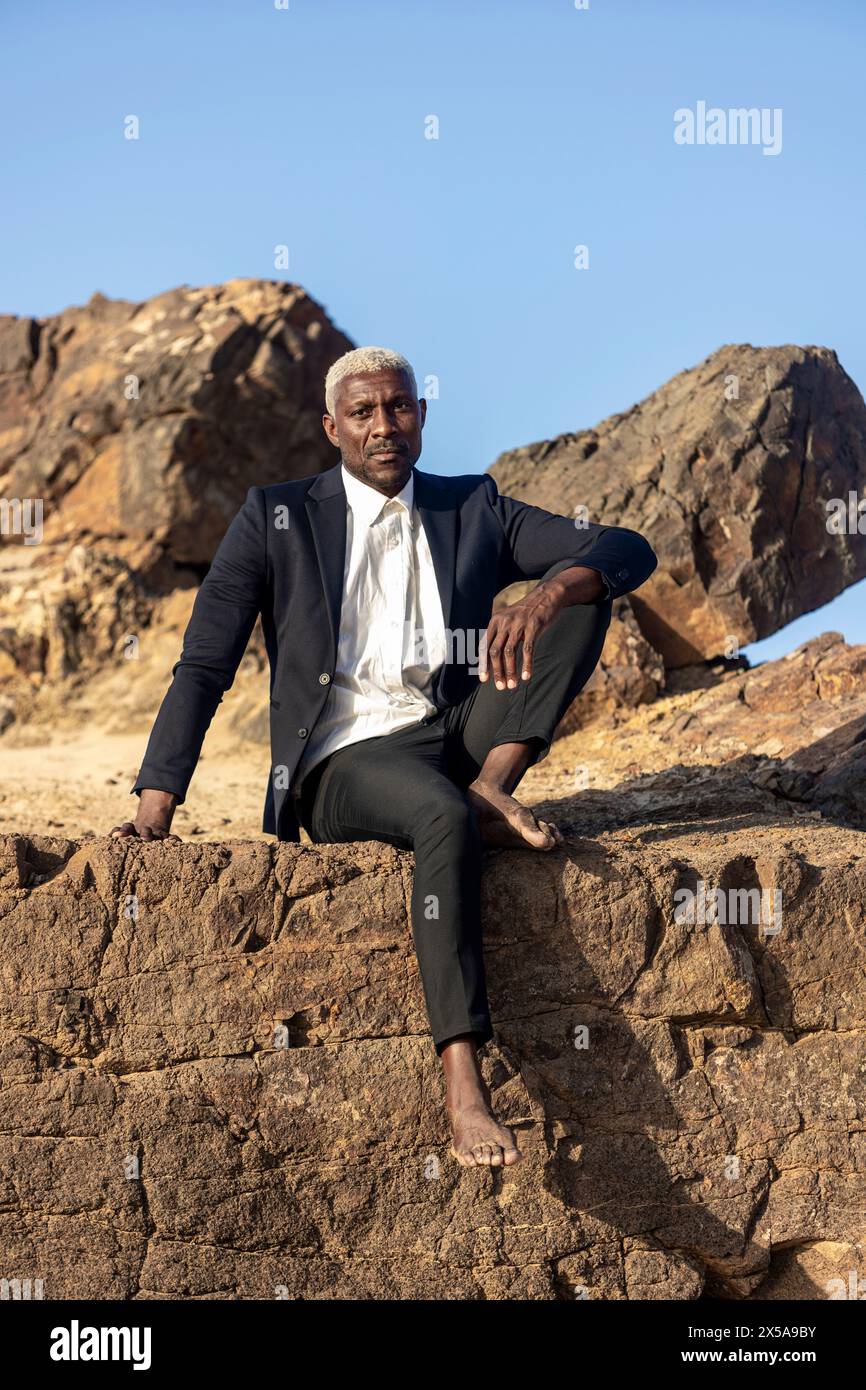 An African American male model, dressed in a formal suit and barefoot ...