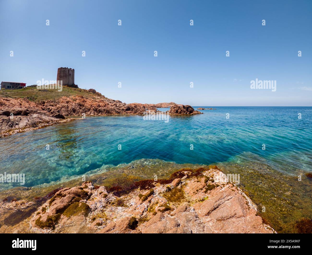 Ancient castle ruins stand on a rocky cliff above the serene blue sea ...
