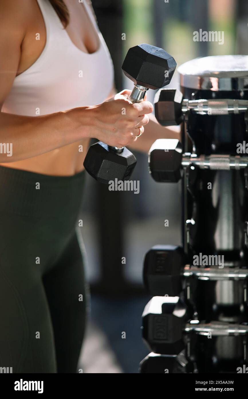 A close-up image of a female athlete's hand as she lifts a dumbbell, focused on fitness at home Stock Photo