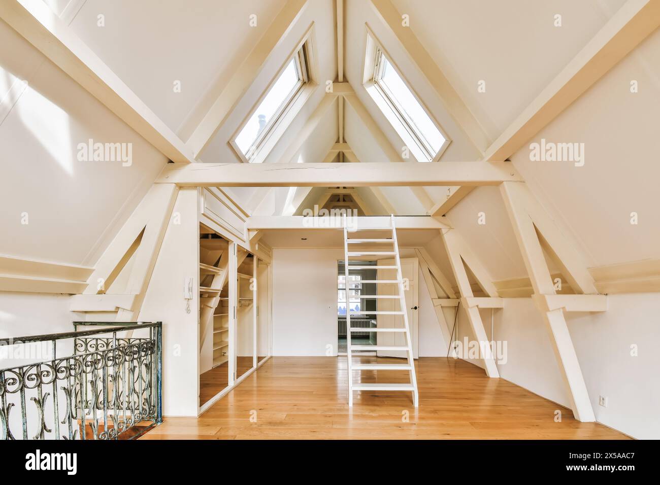 A bright and airy attic room with vaulted ceilings, skylight windows, and polished wooden