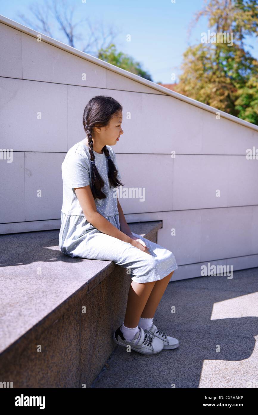 Little girl on the autism spectrum relaxing while walking in the big city Stock Photo