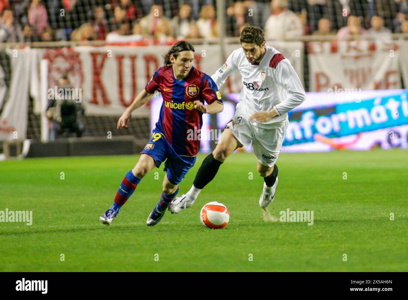 Leo Messi dribbles past Dragutinovic in a thrilling La Liga match at Ramón Sánchez-Pizjuán Stadium. Stock Photo