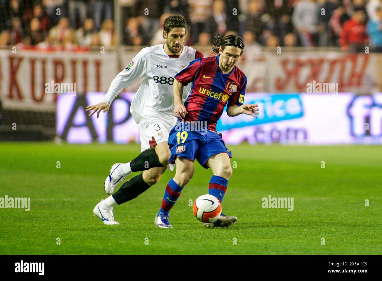Leo Messi dribbles past Dragutinovic in a thrilling La Liga match at Ramón Sánchez-Pizjuán Stadium. Stock Photo