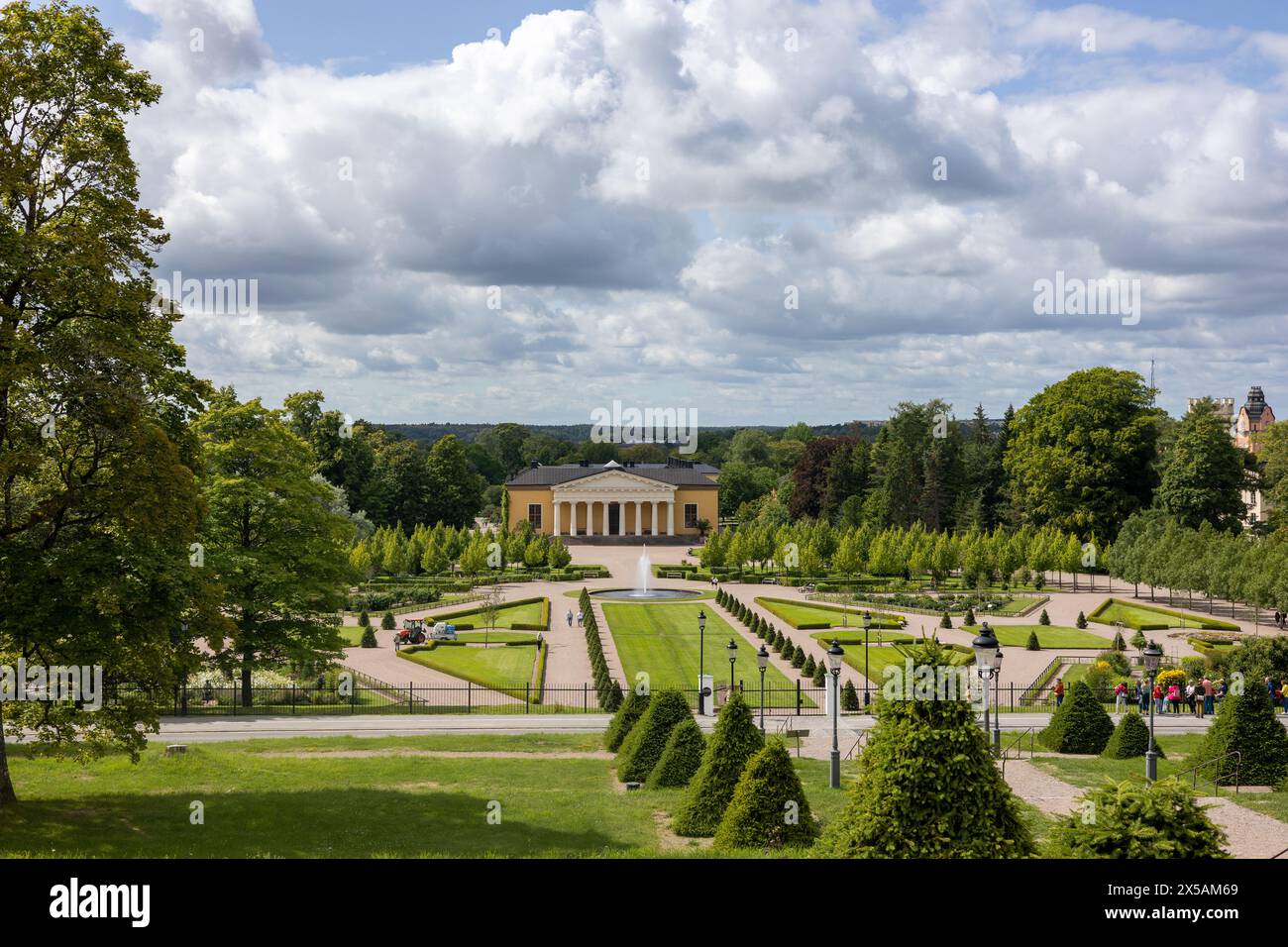 Uppsala, Sweden - July 26 2023: Park, fountain and historical building near royal castle. People visible on street. Stock Photo