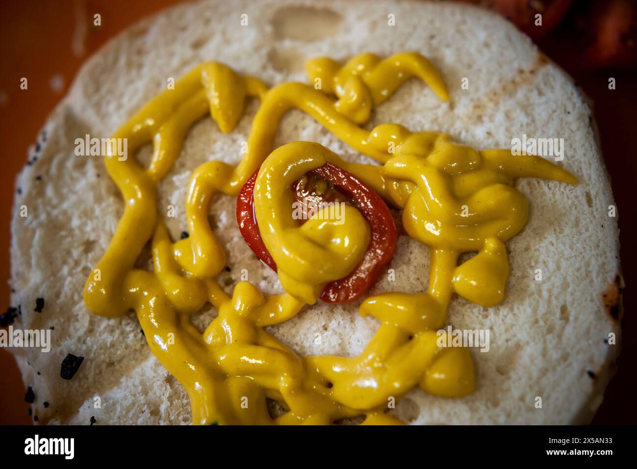 A bagel with with squirts of mustard in a kitchen in New York on Monday May 6, 2024. (© Richard B. Levine) Stock Photo