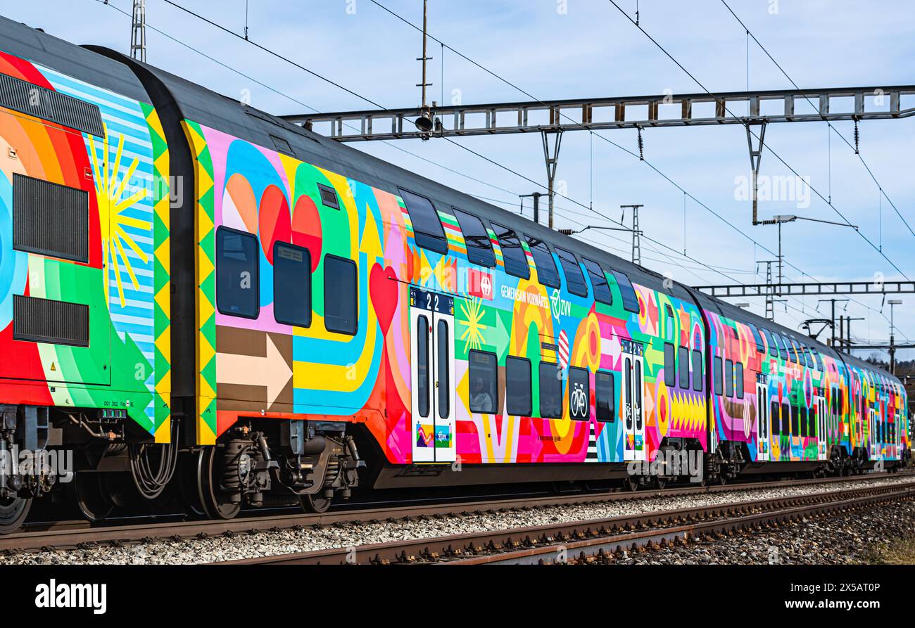 Eine Zürcher S-Bahn der Linie S24 (S-Bahn 24) vom Typ SBB RABe 514 fährt in den Bahnhof Bassersdorf ein. Der Zug trägt die ZVV-Werbung mit dem Titel ' Stock Photo