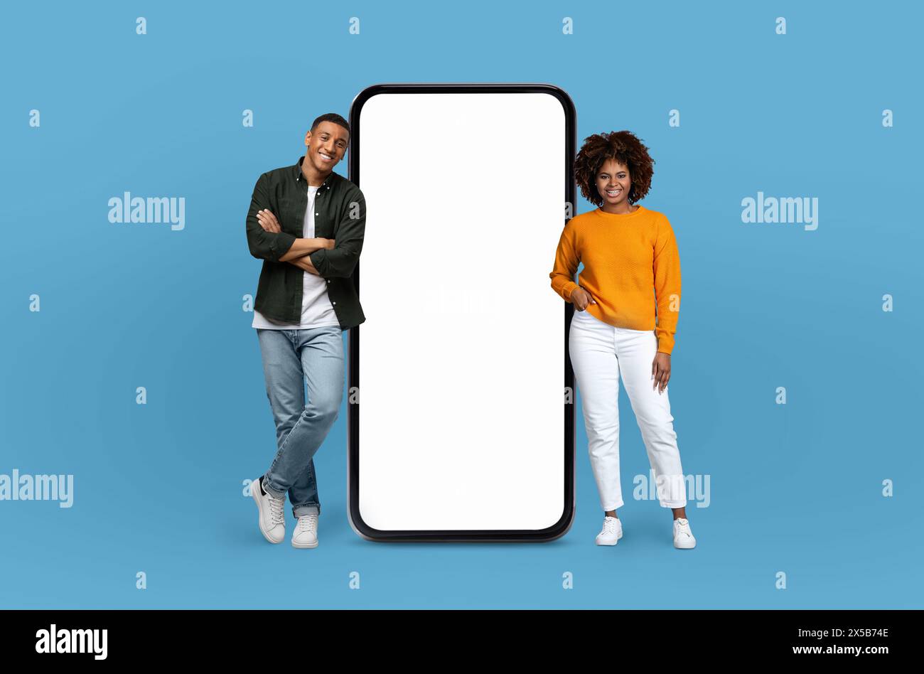 Two African American People Standing Next to A Big Phone Stock Photo