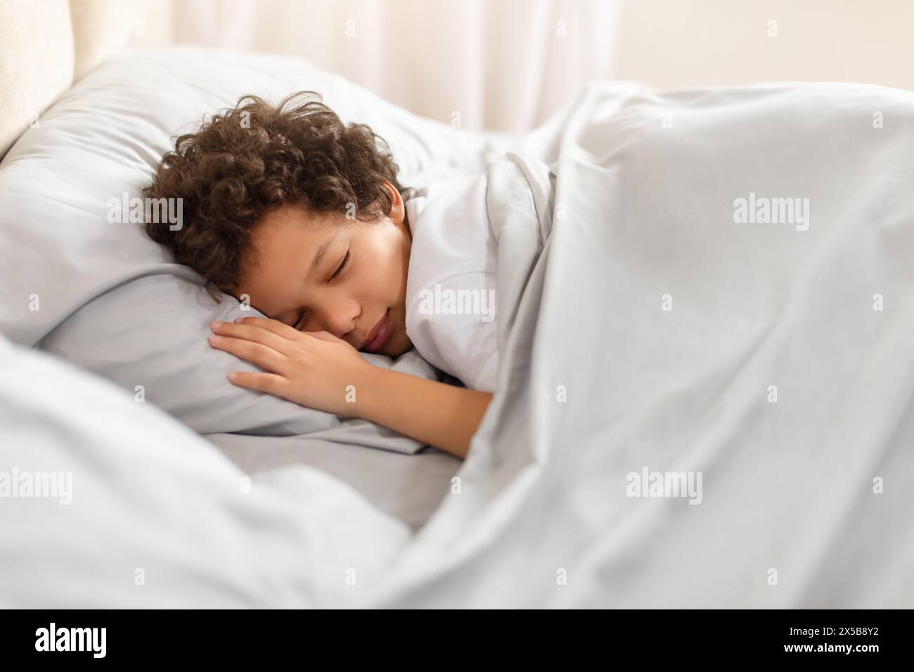 Young Boy Sleeping in Bed With White Sheets Stock Photo