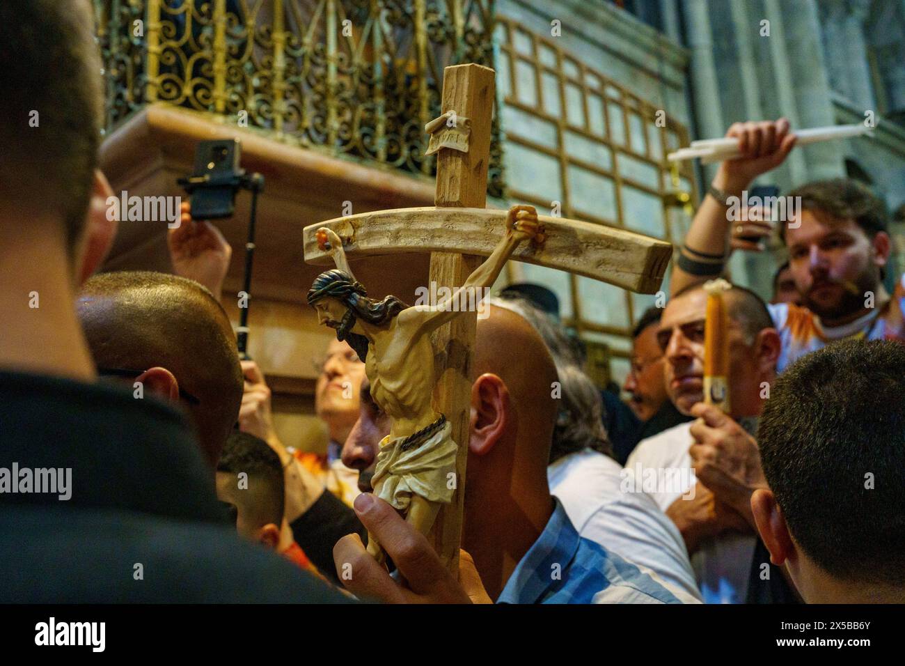 A devotee holds a cross with the image of Jesus before the ceremony of ...