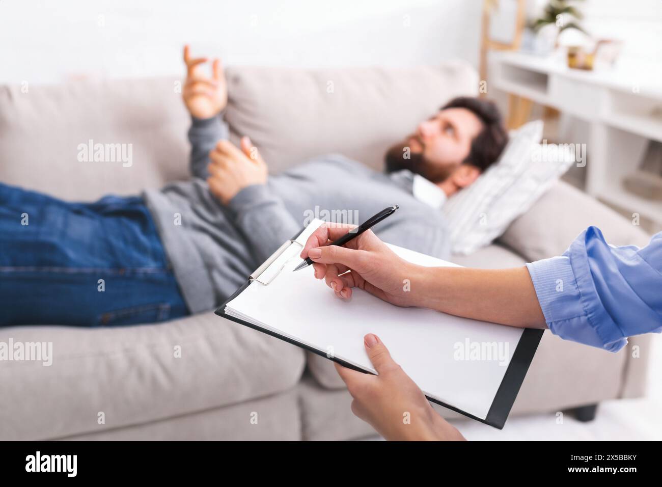 Therapist Taking Notes While Man Discusses Issues During Counseling Session Stock Photo