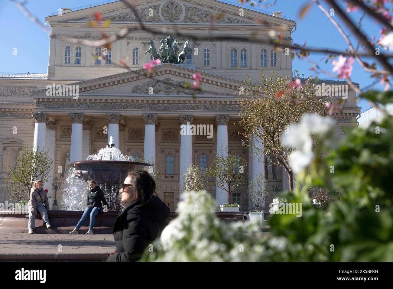 Moscow, Russia. 3rd of May, 2024. Flowering trees with young foliage on the background of the facade of the Bolshoi Theater building on Teatralnaya Square in the center of Moscow, Russia Stock Photo