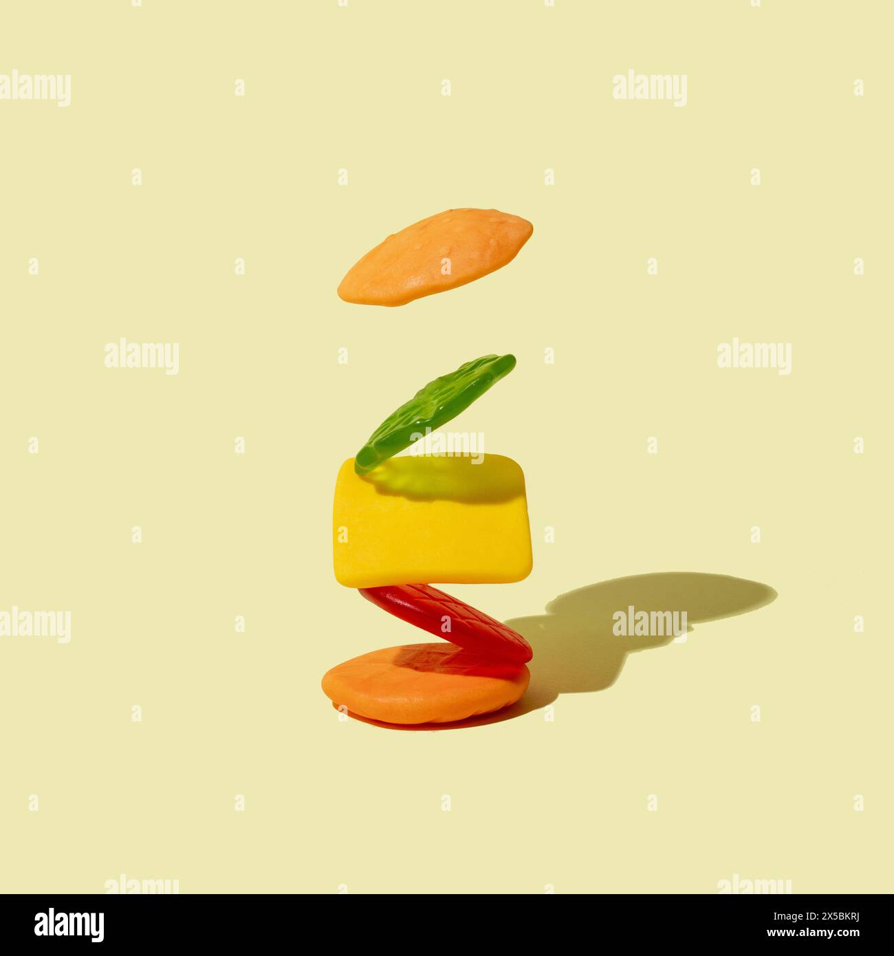 Gummy candy in the shape of a cheeseburger on a light beige background. Minimal junk food concept. Stock Photo