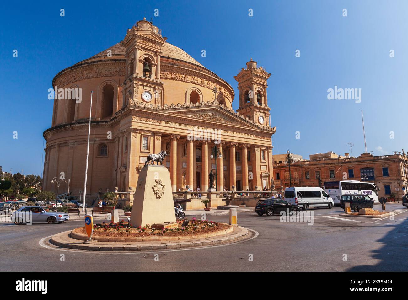 Mosta, Malta - August 25, 2019: Rotunda of Mosta. Exterior of Sanctuary Basilica of the Assumption of Our Lady. Street view with people and cars on th Stock Photo