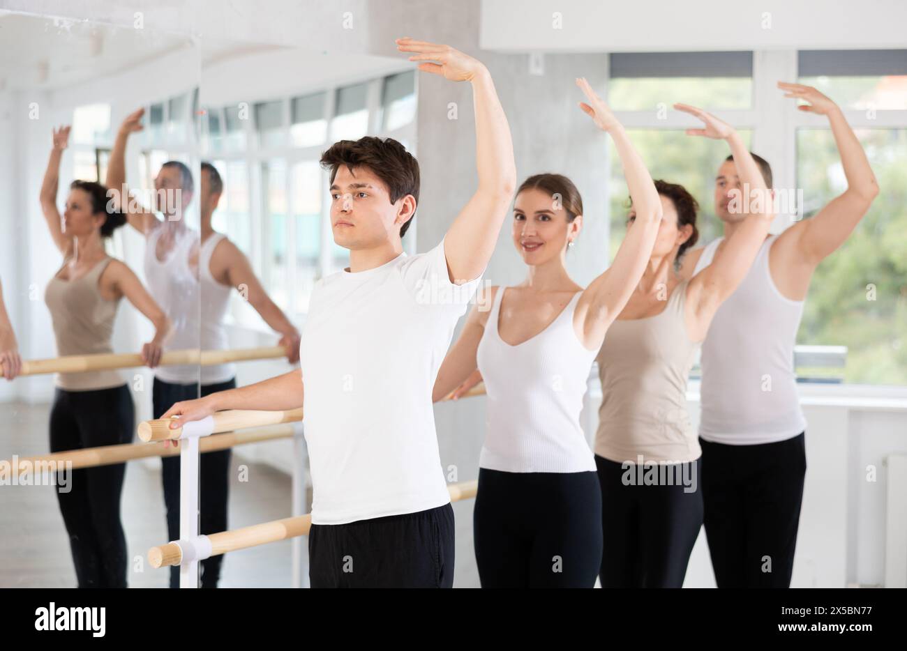 Guy performing third position at barre during group ballet class Stock ...