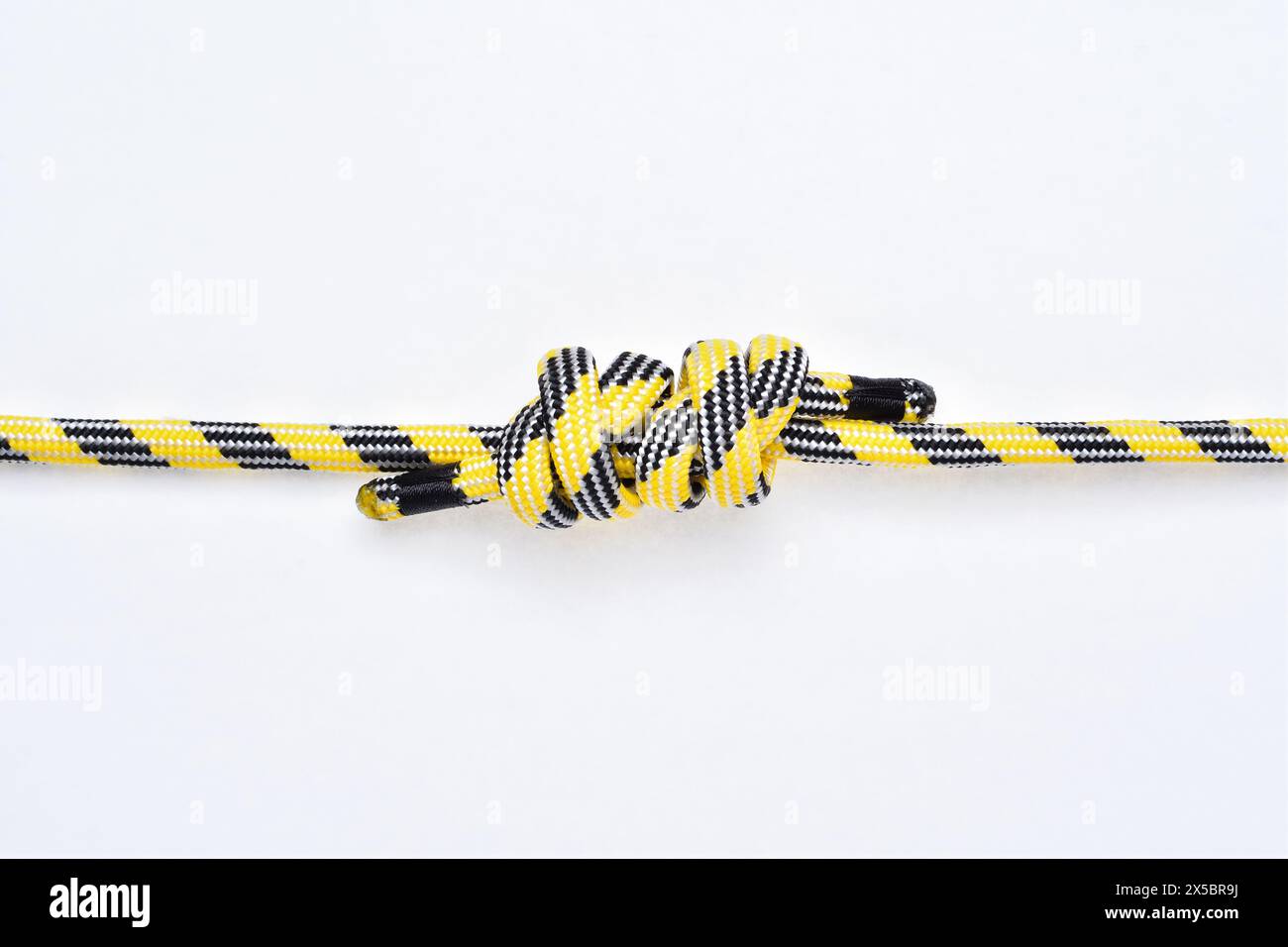 Double Fisherman's knot on yellow and black nylon rope on white background. Stock Photo