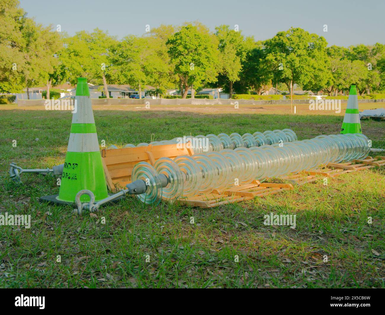 High voltage electricity line insulators on the green grass. For high-voltage power lines. Green safety cone with turnbuckles with green trees Stock Photo