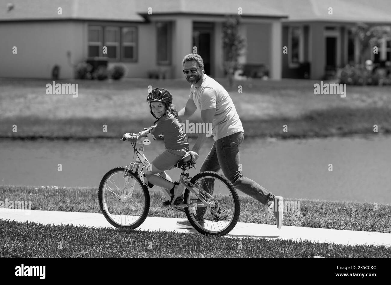 Father and son in a helmet riding bike. Little cute adorable caucasian boy in safety helmet riding bike with father. Family outdoors summer activities Stock Photo