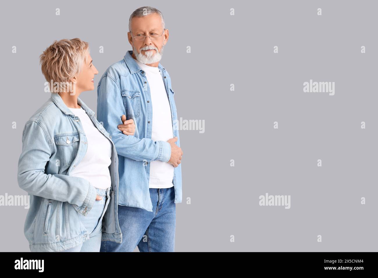 Mature couple in denim clothes walking on light background Stock Photo ...