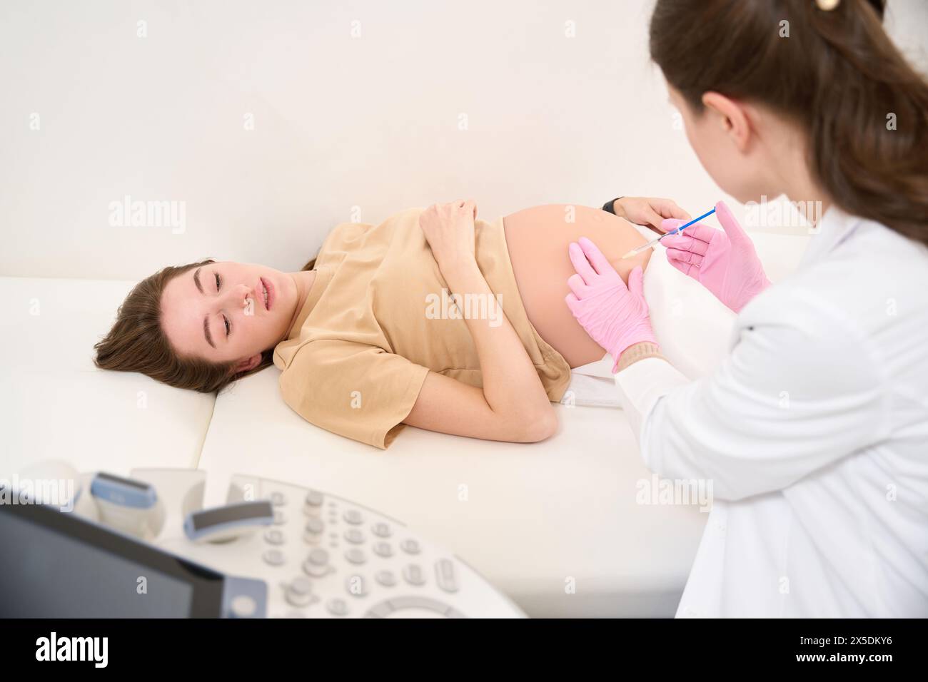Gynecologist doing injection with syringe in pregnant belly of woman in ...